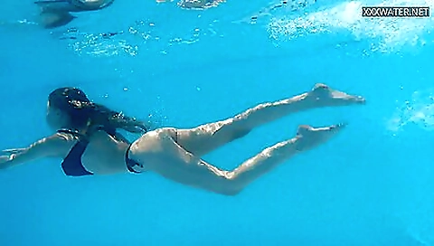 Sexy brunette in a t-shirt and shorts is in the pool